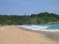 Nai Harn Beach is overlooked by wind turbines on top of the headland